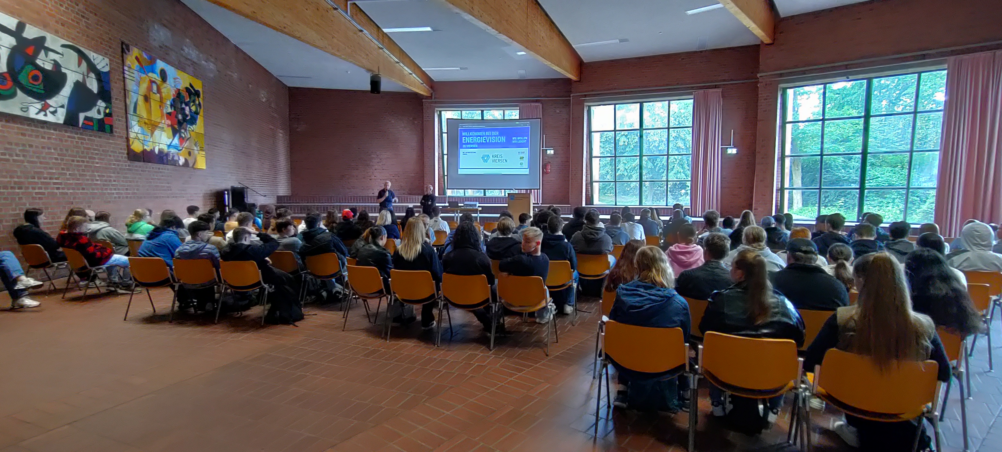 Auf dem Bild ist die Aula mit dem Dozenten und vielen SuS zu sehen zum Auftakt der Veranstaltungen.